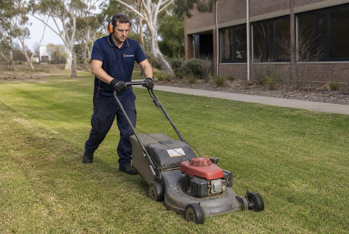 Siguren gardener mowing a coastal residential lawn beside a branded work ute